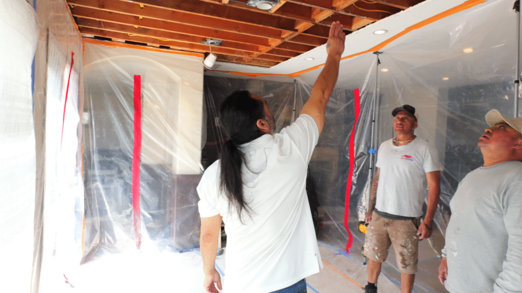 The owner of GR Repair & Maintenance pointing at ceiling structure during a drywall inspection in Long Beach.