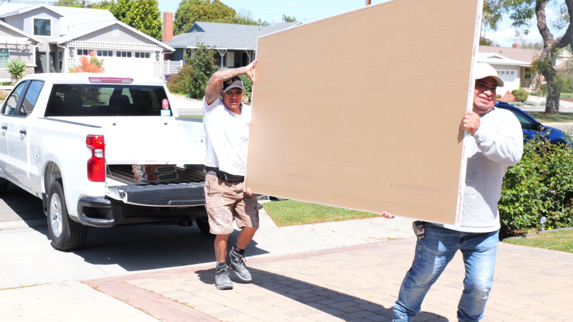 GR Repair & Maintenance carrying drywall sheets in a residential neighborhood in Long Beach